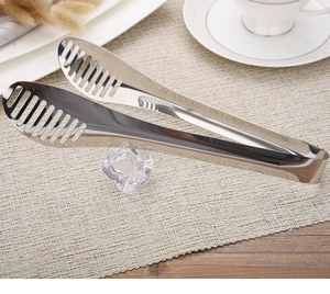 Detailed view of stainless steel food tongs with hollow design on woven placemat decor