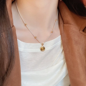 Tiger eye stone round pendant necklace on model with vintage brown suit and white top