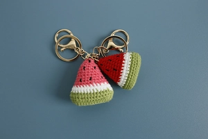 Macro detail of hand-knitted watermelon keychains in red and pink with golden metal clasps