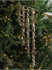 Close-up of sparkling gold glitter branch ornaments on a festive Christmas tree