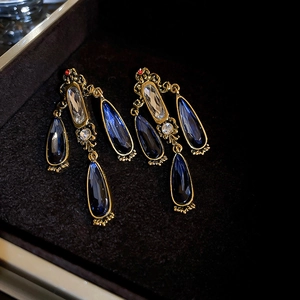 Detail of vintage gold drop earrings with deep blue water drop stones in a jewelry box