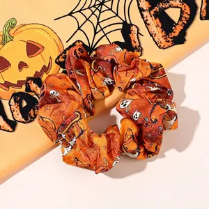 Detail of orange Halloween scrunchie with pumpkin and ghost prints on satin fabric