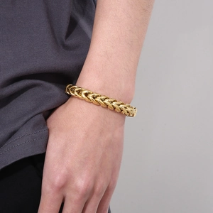 Close-up of a gold dragon bone chain bracelet for men on a male model's wrist