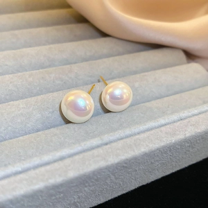 Macro view of mermaid pearl stud earrings with rainbow luster on luxury velvet display