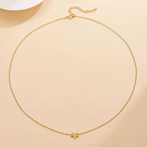 Detail view of a gold S925 sterling silver star necklace with extension chain on beige back