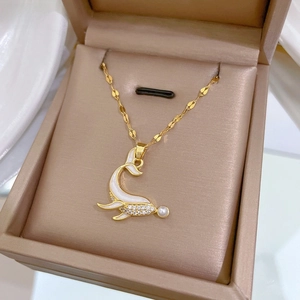 Macro view of gold dolphin pendant with micro-set zircon and pearl on jewelry box