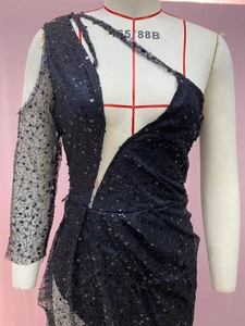 Detail eines schwarzen Paillettenkleides mit asymmetrischer Schulter und Netzhülle