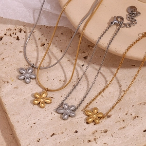Detailed macro of flower charms on 18K gold and silver plated stainless steel chains