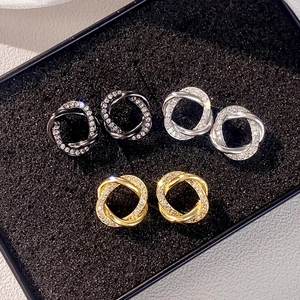 Detail view of intertwined circle earrings in gold, silver and black with zircon stones