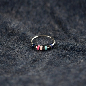 S925 silver fidget ring with five colorful enamel beads on a textured blue fabric background