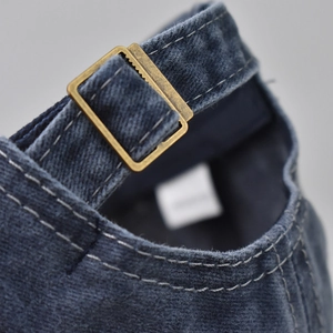 Macro detail of navy washed denim baseball cap with adjustable vintage brass metal buckle