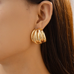 Close-up of golden multi-layered textured geometric hoop earring on model ear