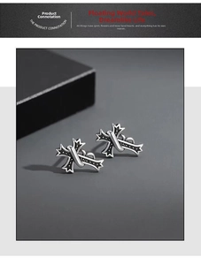 Close-up of vintage 925 silver gothic cross stud earrings with black oxidized texture