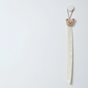 Detail of beige fabric hanging strap with a cute brown plush bear head on a hook