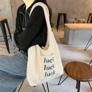Detail of white plush lamb wool tote bag with blue luck embroidery and outer pocket