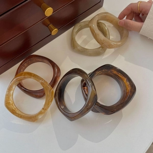 Detail of amber marble resin bangles showcasing tortoise shell patterns on a white table