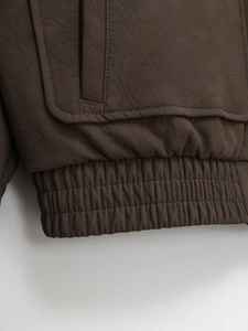 Close-up of dark coffee faux leather jacket showing fine stitching and elastic hem detail