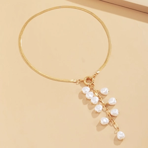 Detailed view of golden snake bone chain necklace with baroque faux pearl tassel pendant