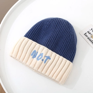 Detailed view of color-block knit beanie with 3D NOT embroidery and soft wool texture