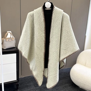 Detail showing soft light green knitted shawl with brown zigzag hem on a mannequin