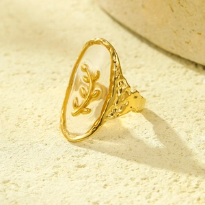 Macro shot of gold ocean shell ring with leaf patterns on textured stone base