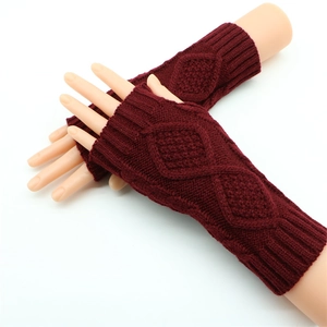 Detail of red cable knit fingerless gloves with diamond patterns and ribbed cuffs