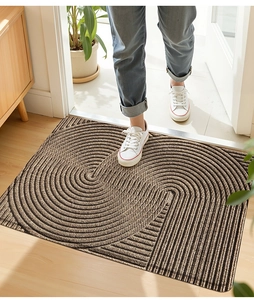 Braune PVC-Schlingenmatte mit konzentrischen Kreisen und Streifen unter weißen Sneakern