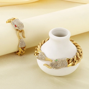Detail of gold Cuban chain bracelet with crystal pavé snake head and gemstone eyes