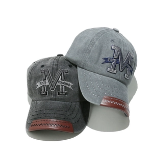 Detail of vintage washed cotton baseball caps with M embroidery and leather stitching
