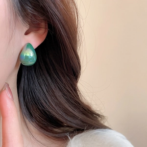 Close-up of elegant aurora green teardrop acrylic stud earring worn on model's ear
