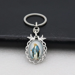 Close-up of silver religious keychain with Virgin Mary portrait and dove details