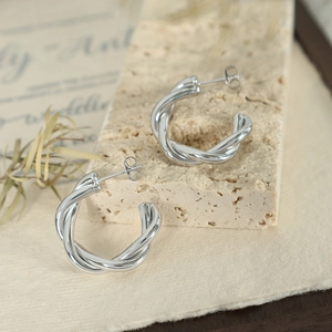 Minimalist silver twisted rope C-shaped hoop earrings on a textured stone base
