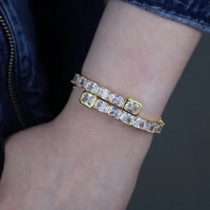 Detail of gold hip hop bangle with clear rectangular cubic zirconia on a model wrist