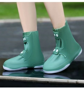 Waterproof silicone shoe covers in sage green with high-top design and decorative buttons