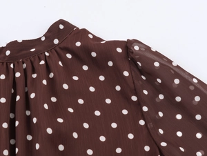 Dettaglio macro dell'abito in chiffon marrone a pois con scollo arricciato