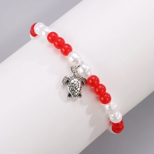 Detalle de pulsera de cuentas con ágata roja, perlas blancas y colgante de tortuga plateada