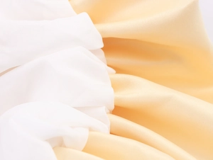 Détail du tissu satiné blanc et champagne avec une texture soyeuse et élégante