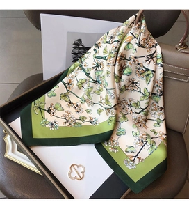 Macro detail of floral and butterfly print silk scarf on a luxury handbag