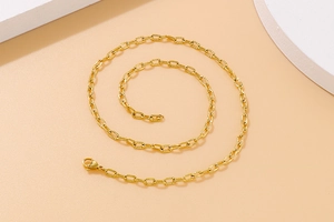 Close-up of gold chunky hammered textured chain necklace with lobster clasp on beige background