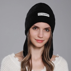 Winter women's black ribbed knit beanie with white letter patch in a minimalist style