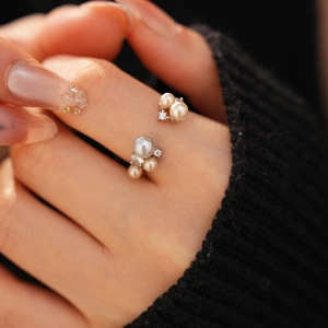 Detail of elegant open ring featuring cream pearls and sparkling zircon on model finger