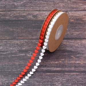 Red and white heart-shaped satin ribbon rolls for gift wrapping on a dark wood table