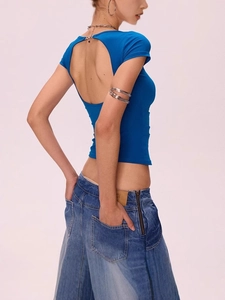 T-shirt bleu moulant dos nu avec épaules dénudées et jean sur un fond rose poudré