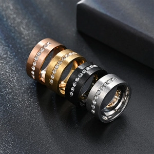 Detail of four brushed stainless steel rings with rhinestones in gold, black, and silver