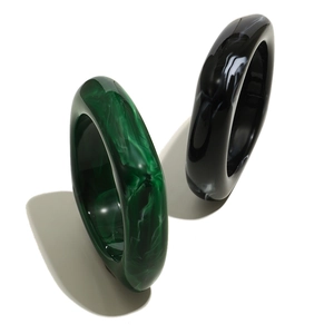 Detailed macro shot of chunky marble resin bangles in dark green and smoky black