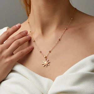 Detailed view of a gold sun pendant necklace with opal stone worn by a female model