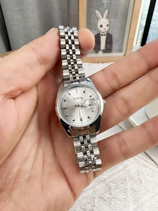Close-up of elegant silver women's watch with steel strap and date display function