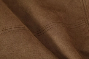 Macro view of brown suede bomber jacket fabric with detailed double-stitched seams