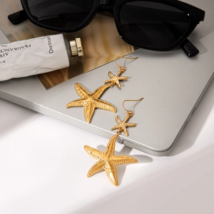 Detail of 18k gold plated starfish drop earrings with hammered texture and tiny crystal