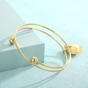 Detailed close-up of double-layer gold stainless steel bracelet with heart pendant charm